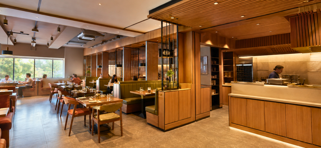 Elegant finished restaurant dining area with warm wood panelling and green booth seating